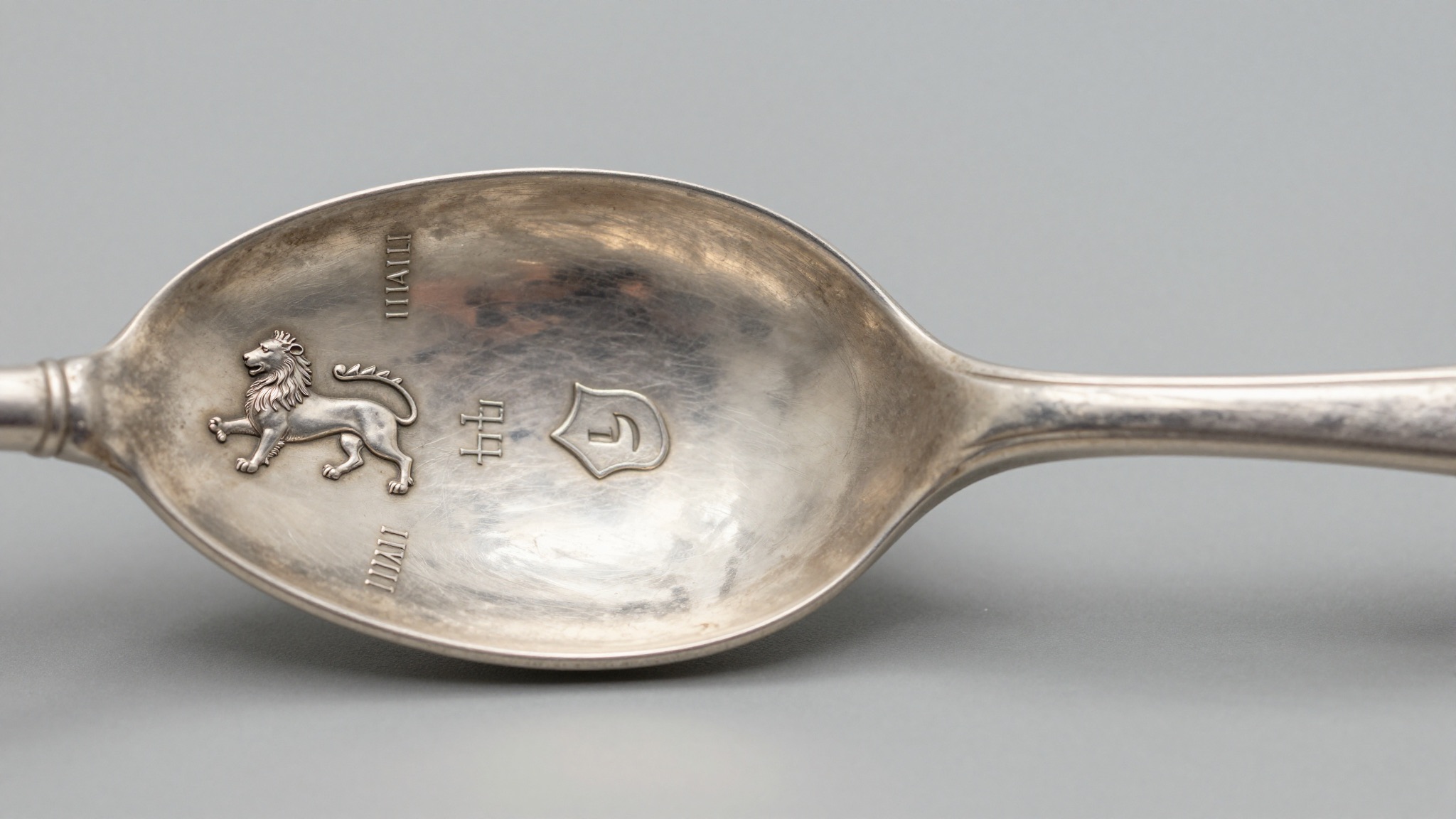 Macro photo of antique British silver hallmarks showing a date letter in a shaped shield beside the assay marks