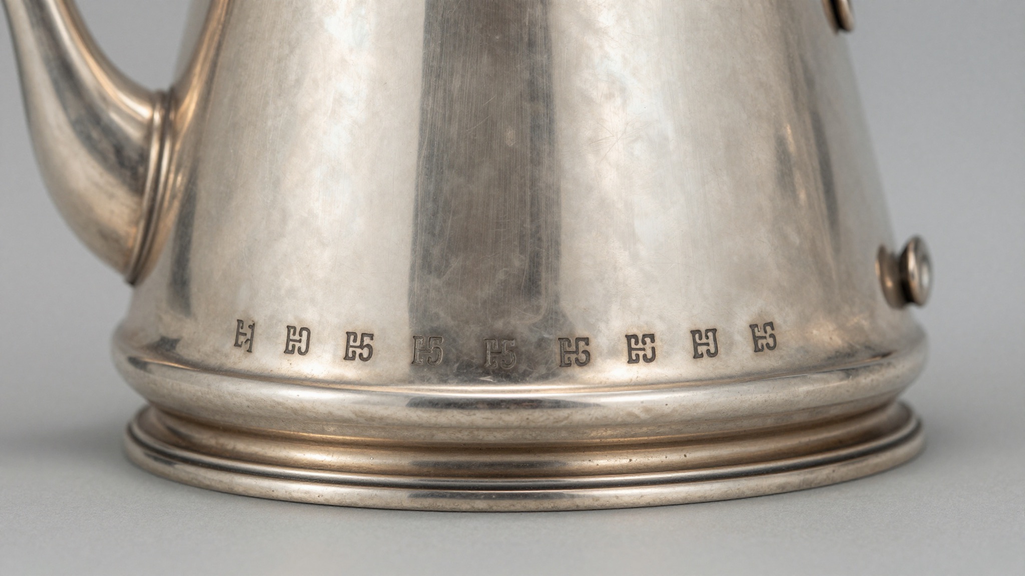 Underside of an antique silver teapot showing a row of struck silver hallmarks