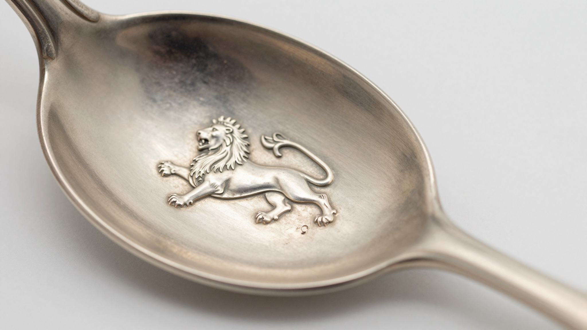 Macro photo of a silver hallmark showing a lion passant beside a stamped number